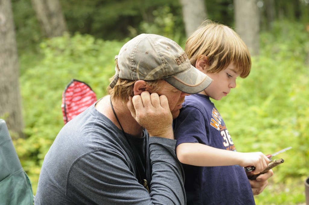 Dad teaching child to whittle