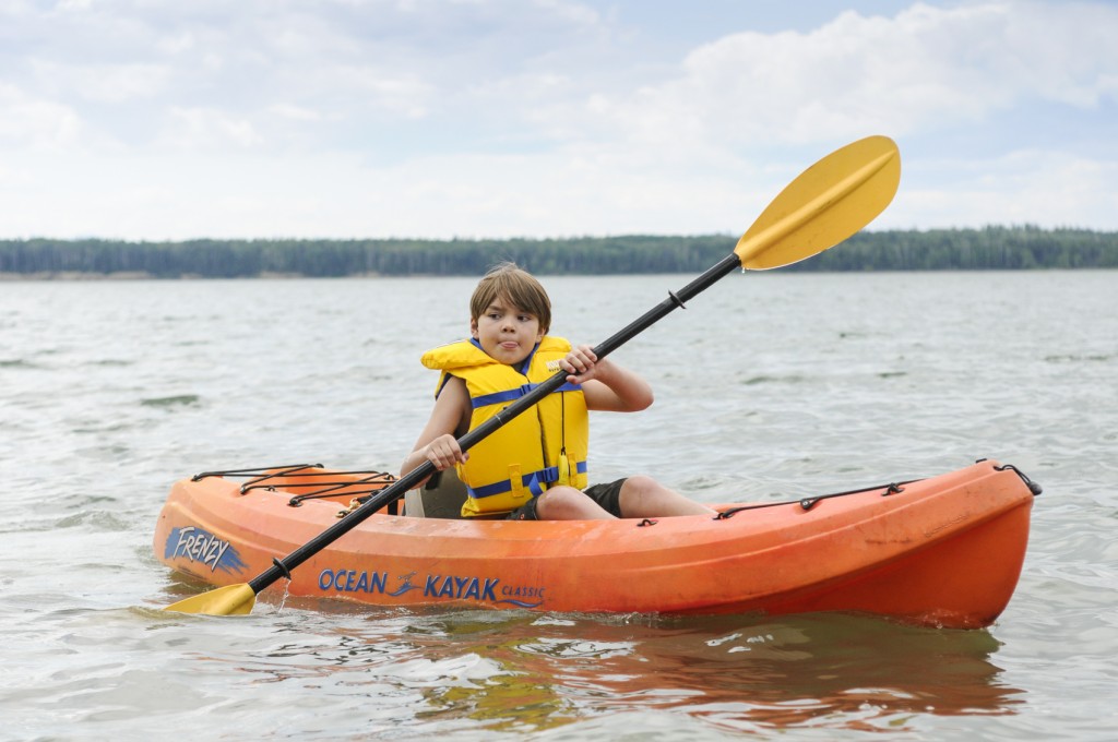 child kayaking on lake